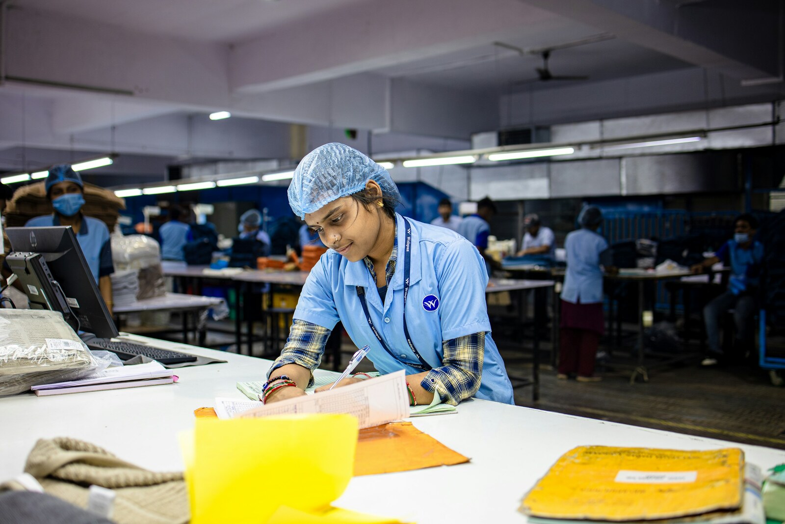 A supervisor working through job cards against a production schedule on the factory floor