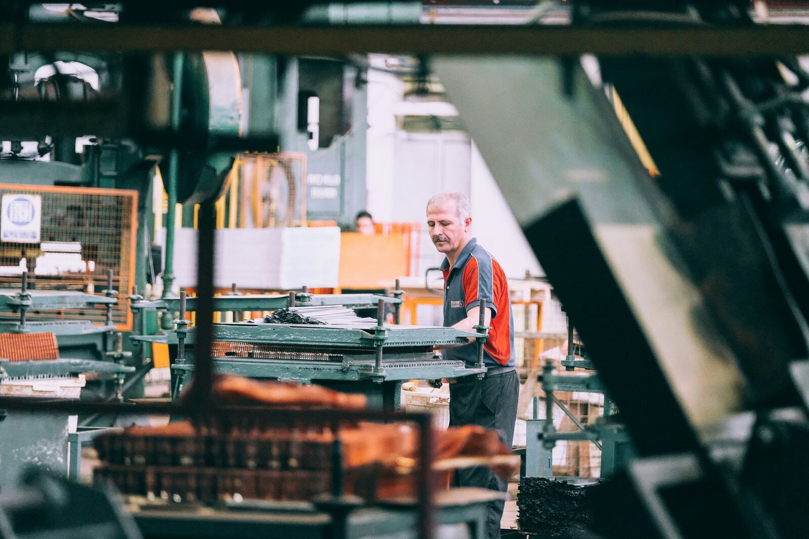 A machine operator working between presses on a manufacturing floor
