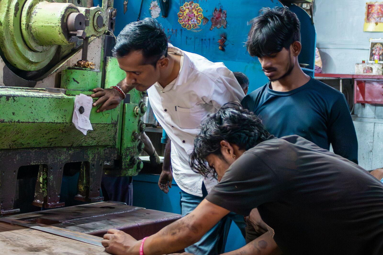 Operators working a mechanical press together on an Indian factory floor