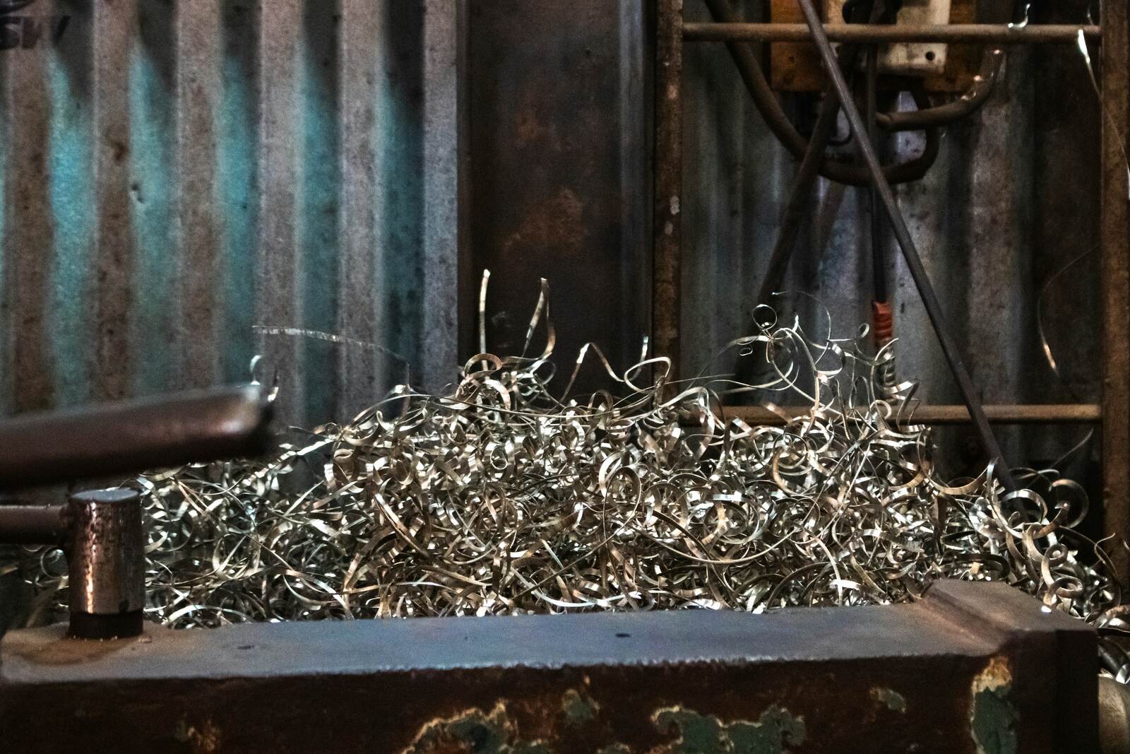 A tray of metal swarf and offcuts collected beside a running machine