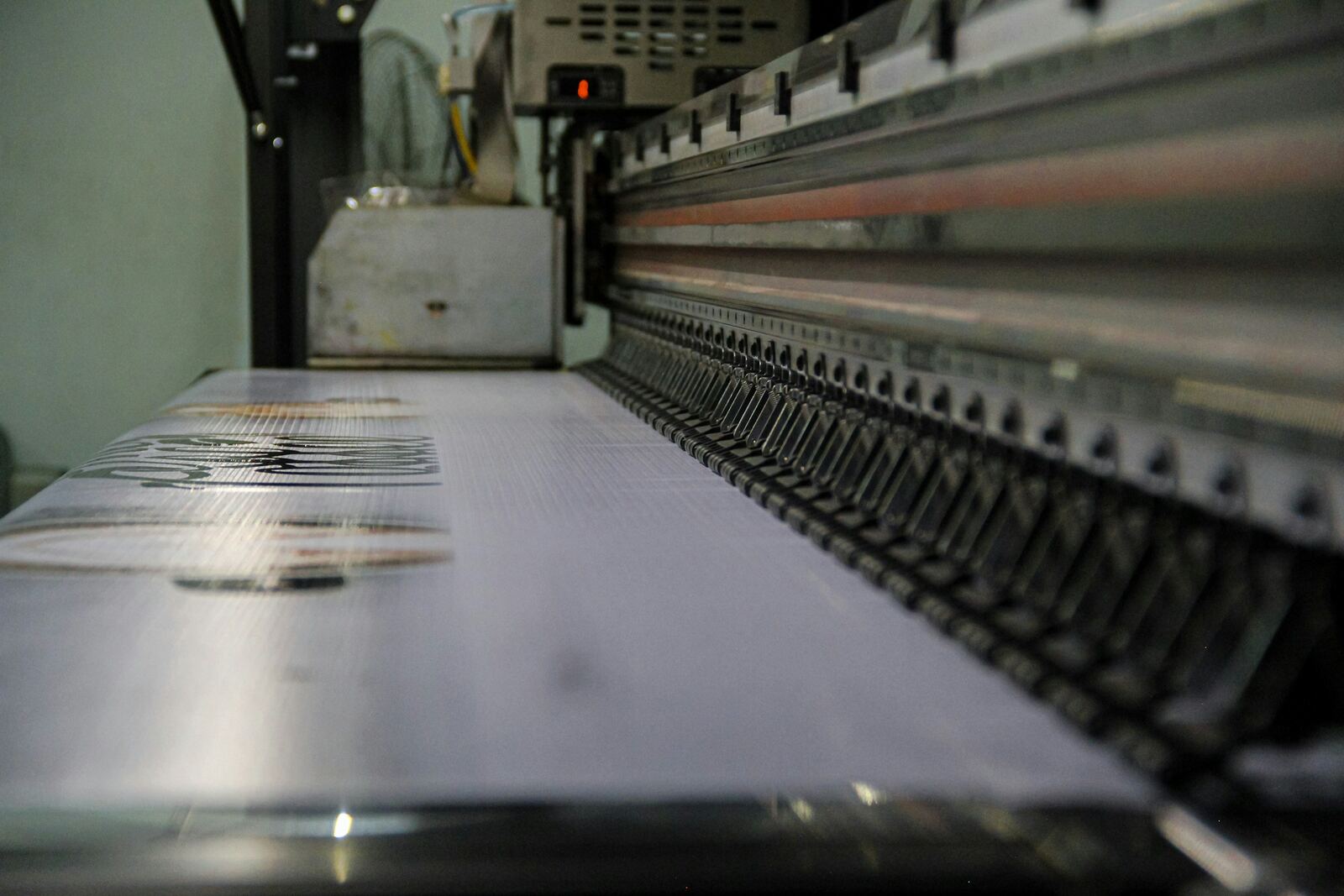 Printed sheets feeding through the grippers of a running offset press